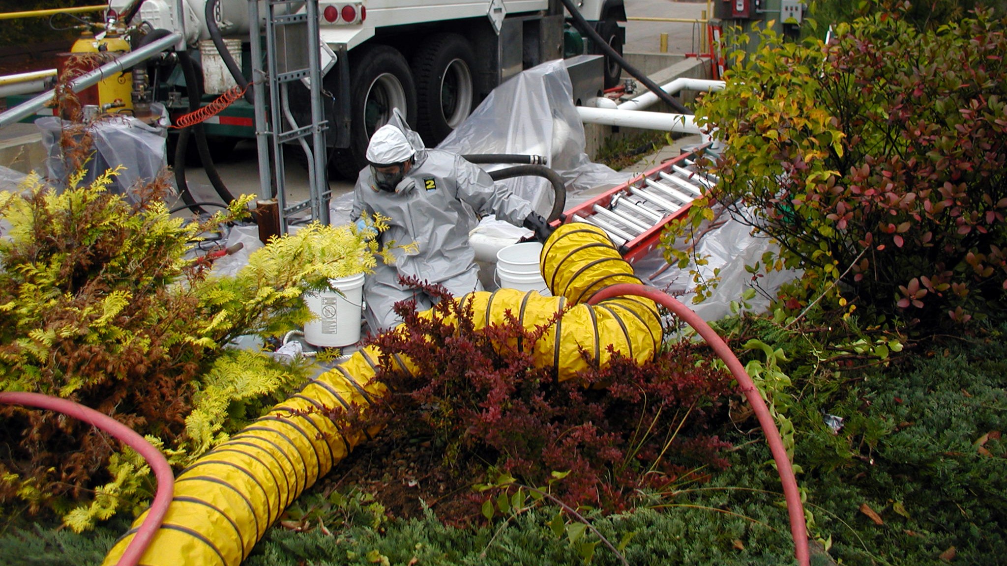 NEDT staffer in protective gear managing hosing connected to NEDT vacuum truck.