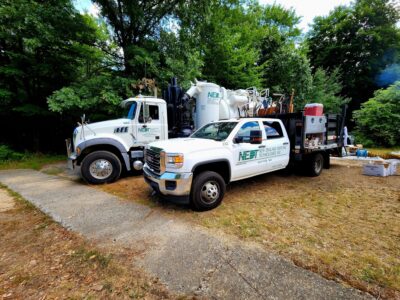 An NEDT Spill Response vehicle and Vacuum truck deployed at a home. The spill response truck contains first response equipment and worksite tools. The vacuum truck is used to clean up contaminated materials, typically oil and soil.