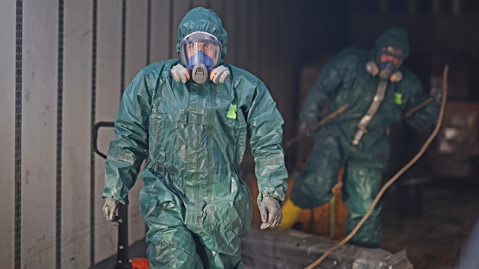 Two NEDT staffers in protective gear work on cleaning up a chemical spill.
