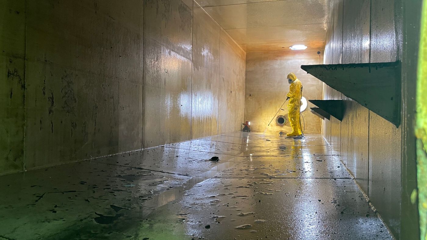 NEDT technician cleaning confined industrial space.