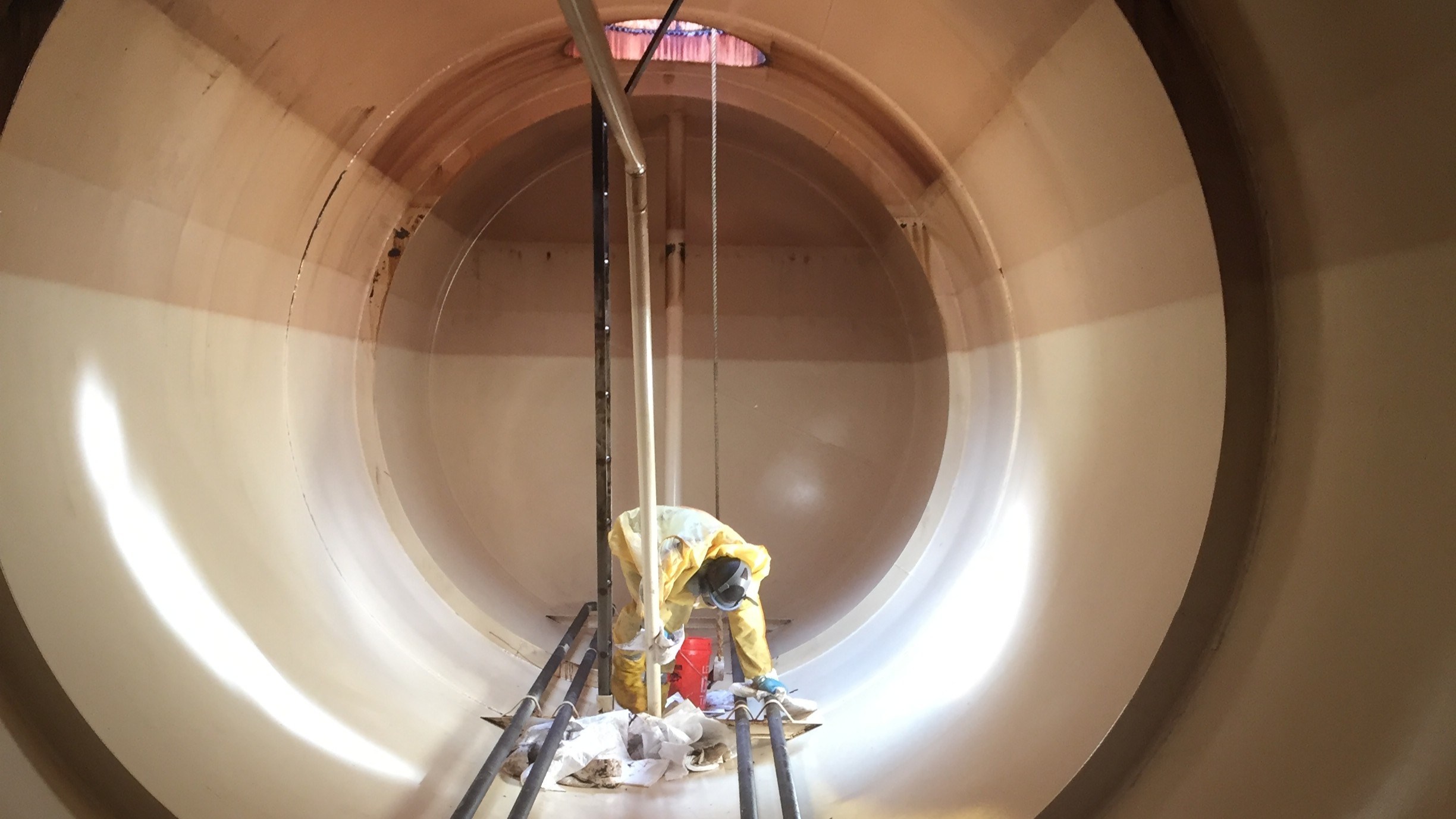 NEDT staffer in protective gear lowered into a tank for cleaning and inspection.