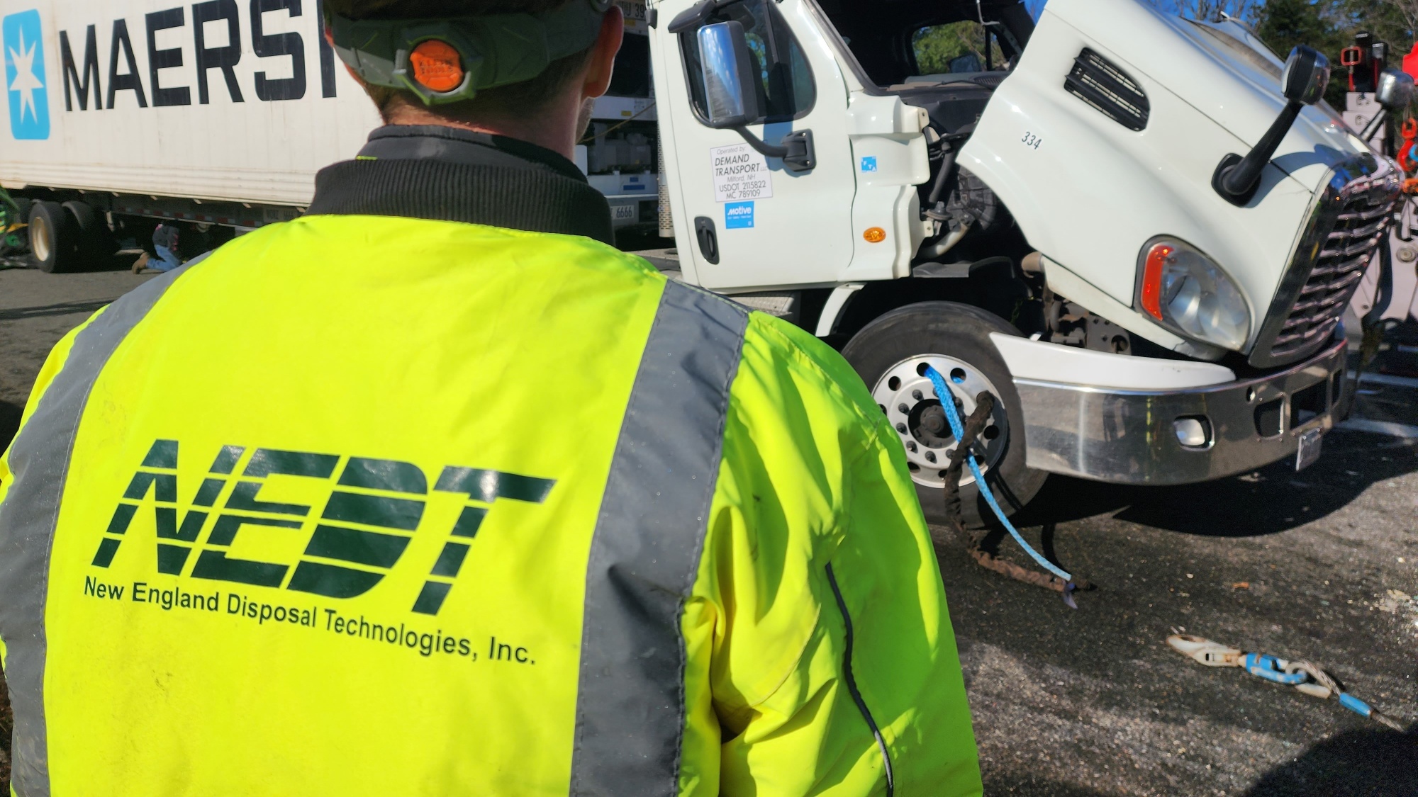 NEDT staffer stands in front of a crashed semi truck and trailer during spill response.
