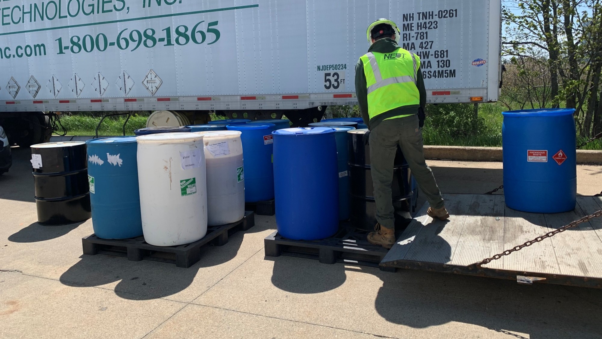NEDT technician loading 55 gallon drums of hazardous waste into an NEDT truck.